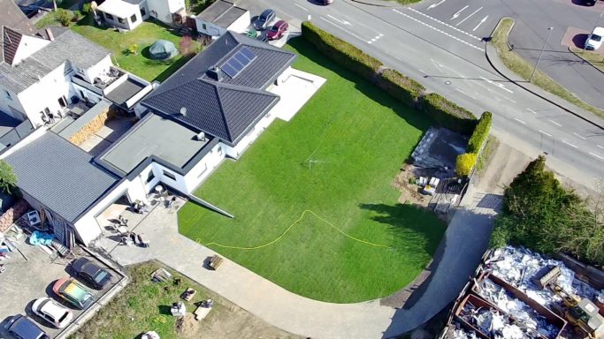 Rollrasen, Terrasse, Pflasterfläche Luftaufnahme eines Hauses mit großem Garten und angrenzender Straße.