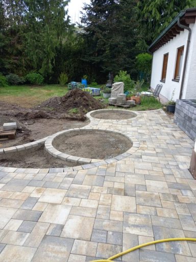Gartenanlage Neu Neu gestalteter Gartenbereich mit gepflastertem Boden und angelegten Blumenbeeten.