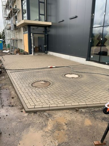 Pflasterfläche Gepflasterte Fläche vor einem Gebäude mit zwei runden Ausschnitten.