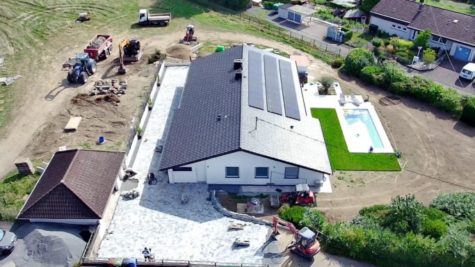 Poolbau und Pflasterarbeiten Haus mit Solarpanelen, Pool und gepflegtem Garten in ländlicher Umgebung.